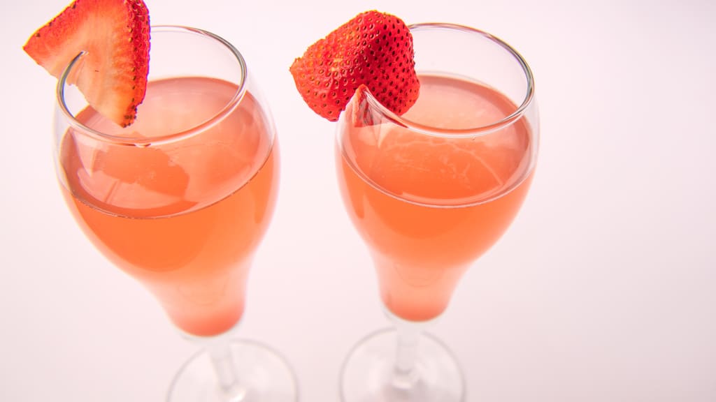 Two mimosas garnished with strawberries